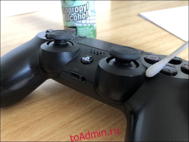 Контроллер DualShock 4 с ватной палочкой рядом с бутылкой изопропилового спирта.